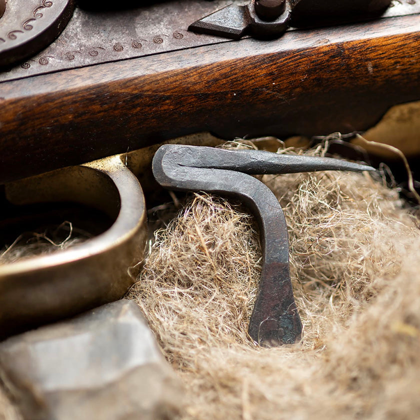 An 18th Century Pickering tool used for black powder shooting sits on tow next to a black powder rifle